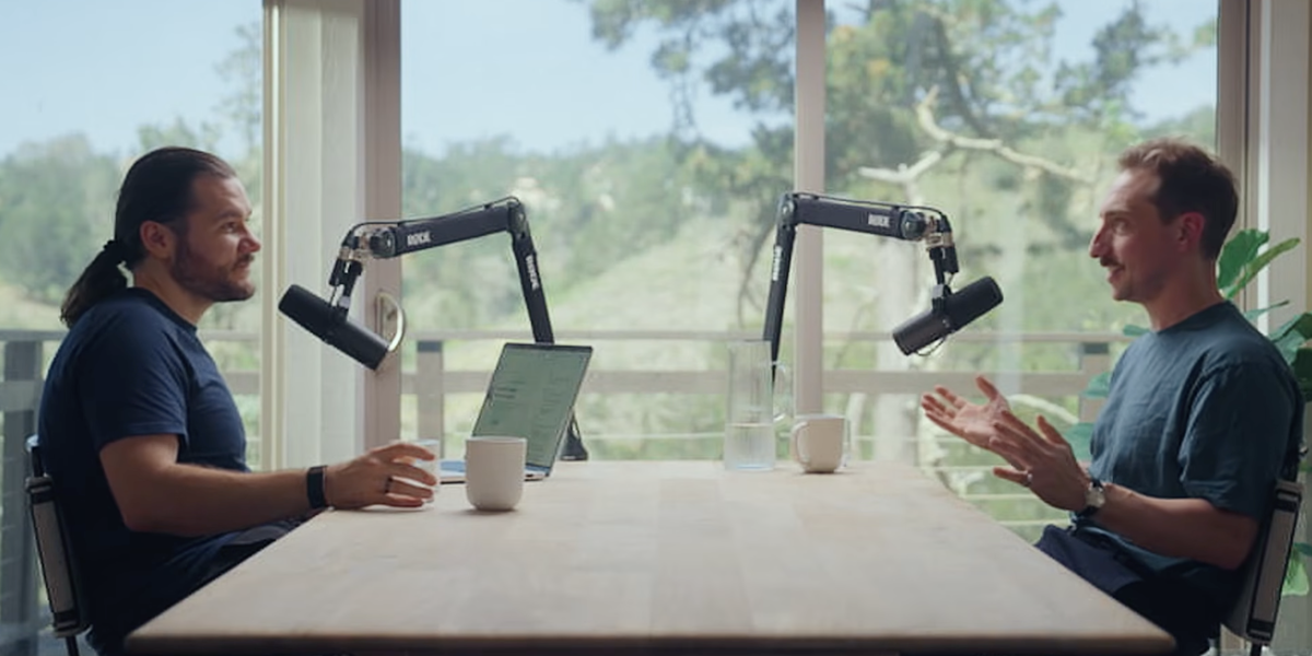 A photo of Jaques Carolan and Juan Benet recording a podcast infront of a big window with a lush garden outside