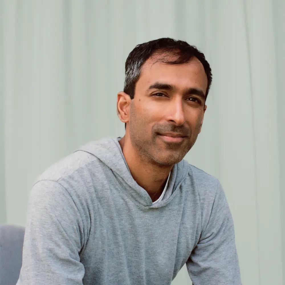 A photo of Suraj Bramhavar in front of a blue curtain.