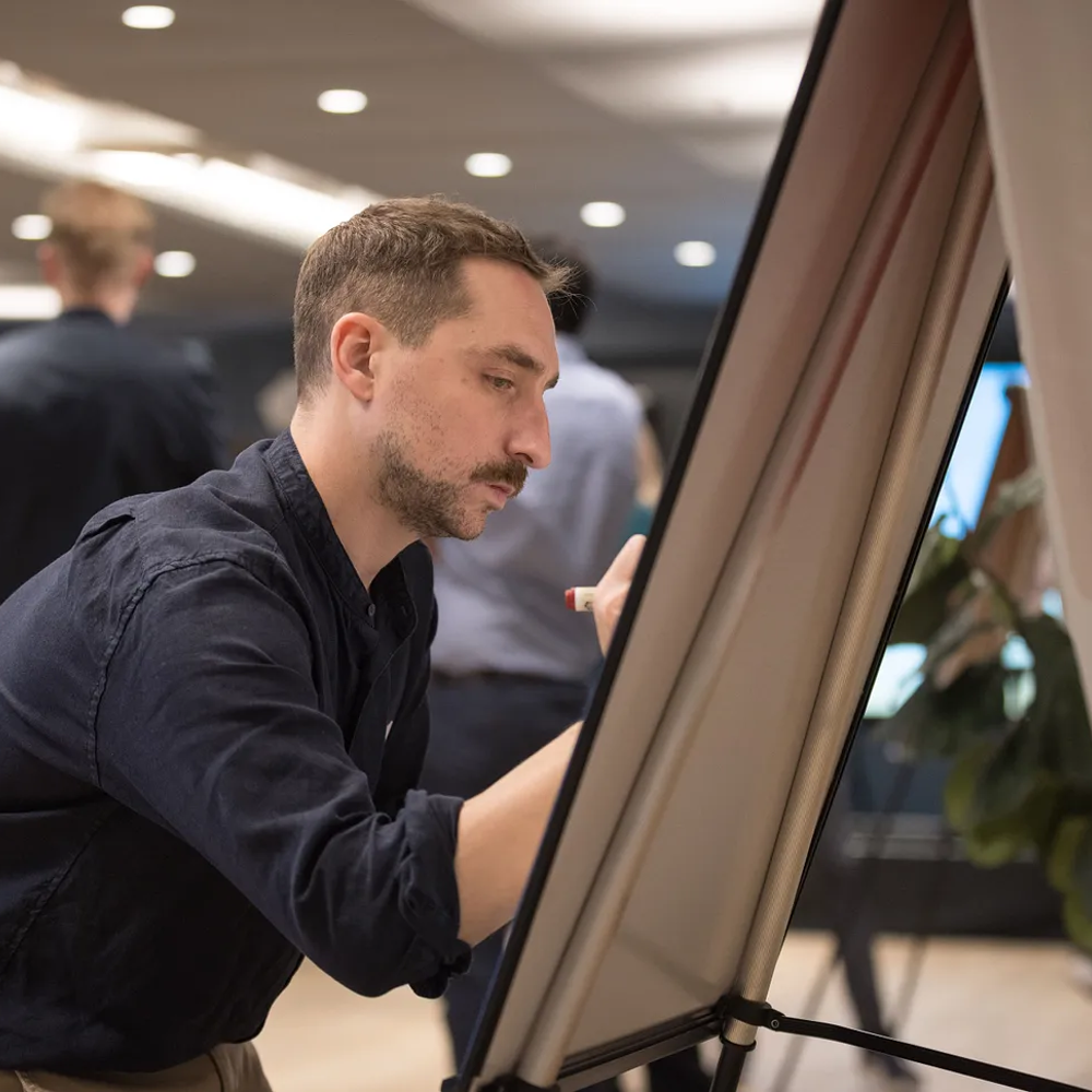 A photo of Jacques writing on a white board.