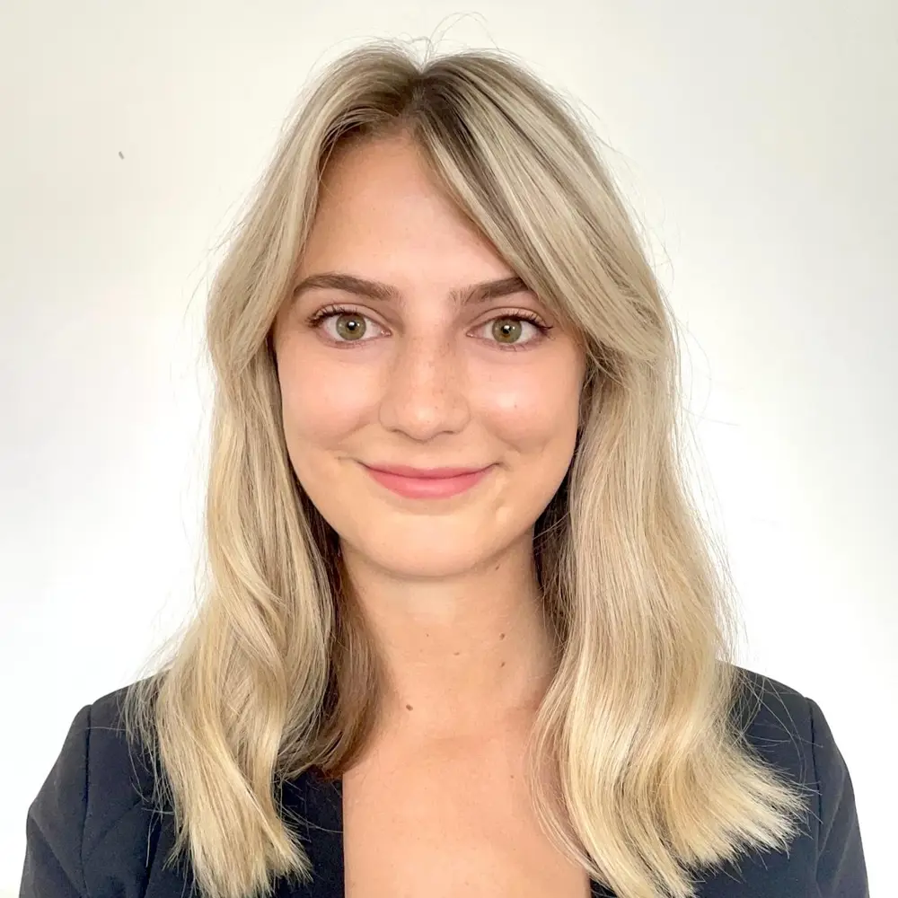 Photo of Caitlyn Kubala standing against a cream wall