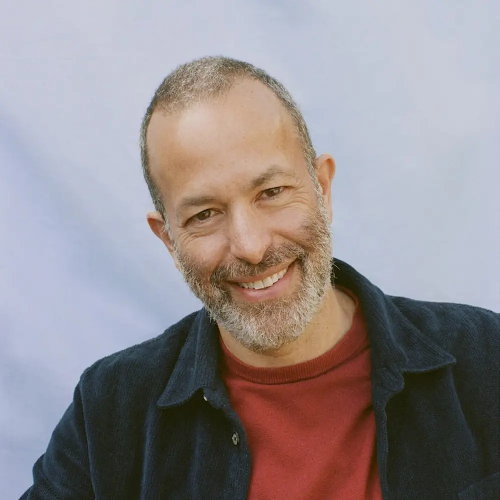 Photo of Nathan Wolfe smiling, against a blue background