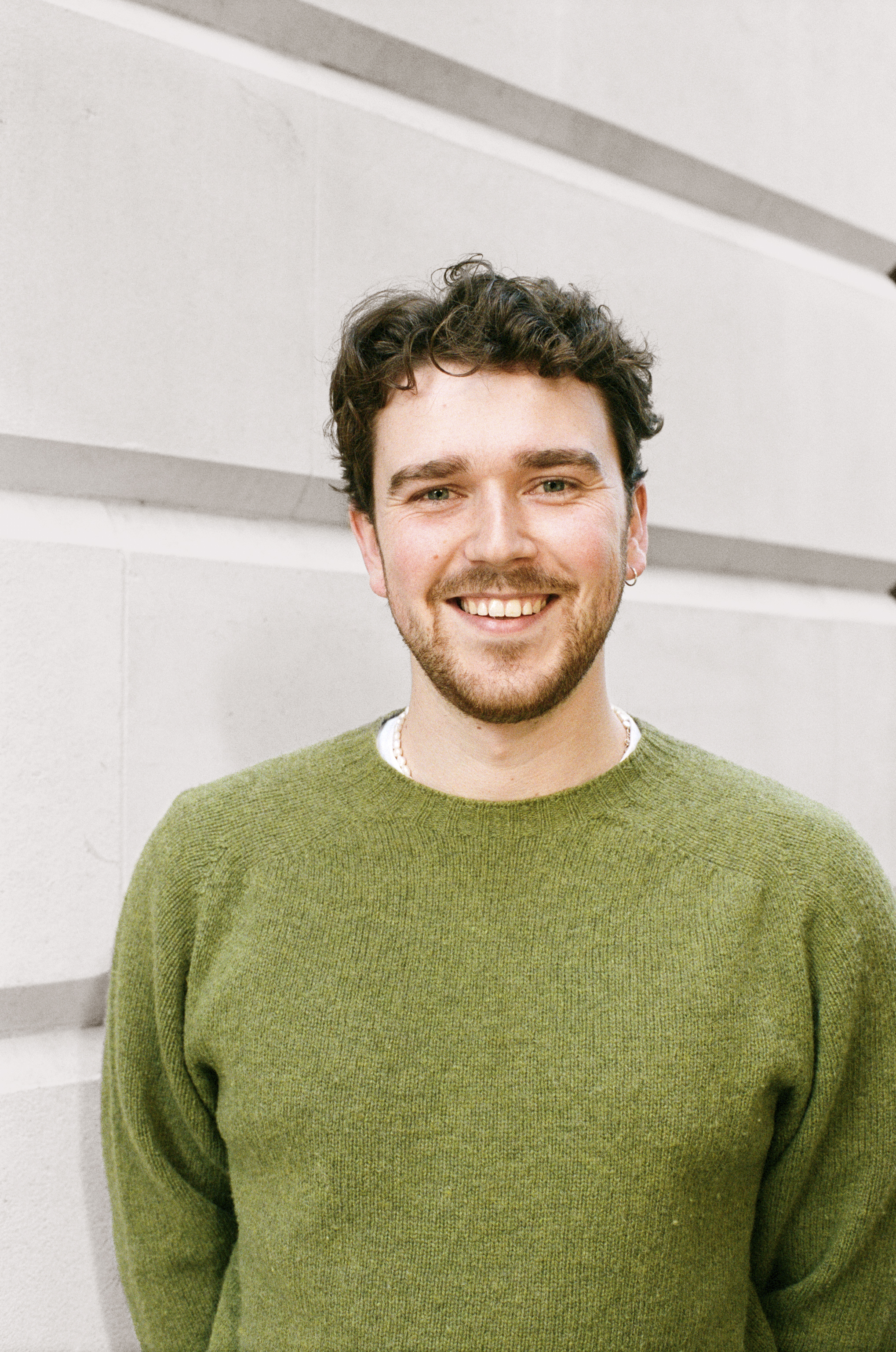 A photo of George Horner smiling against a white call. 