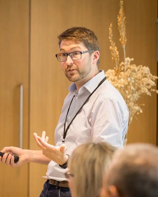 A photo of Mark Symes presenting at an event.