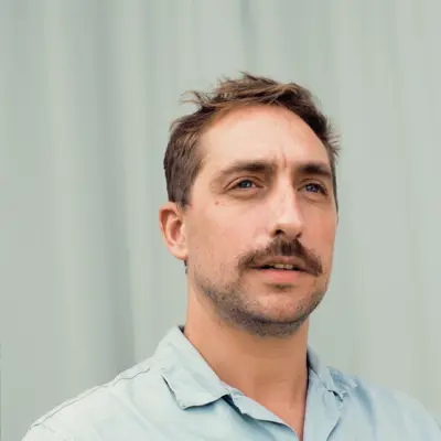 Headshot of Jacques Carolan standing against a grey curtain