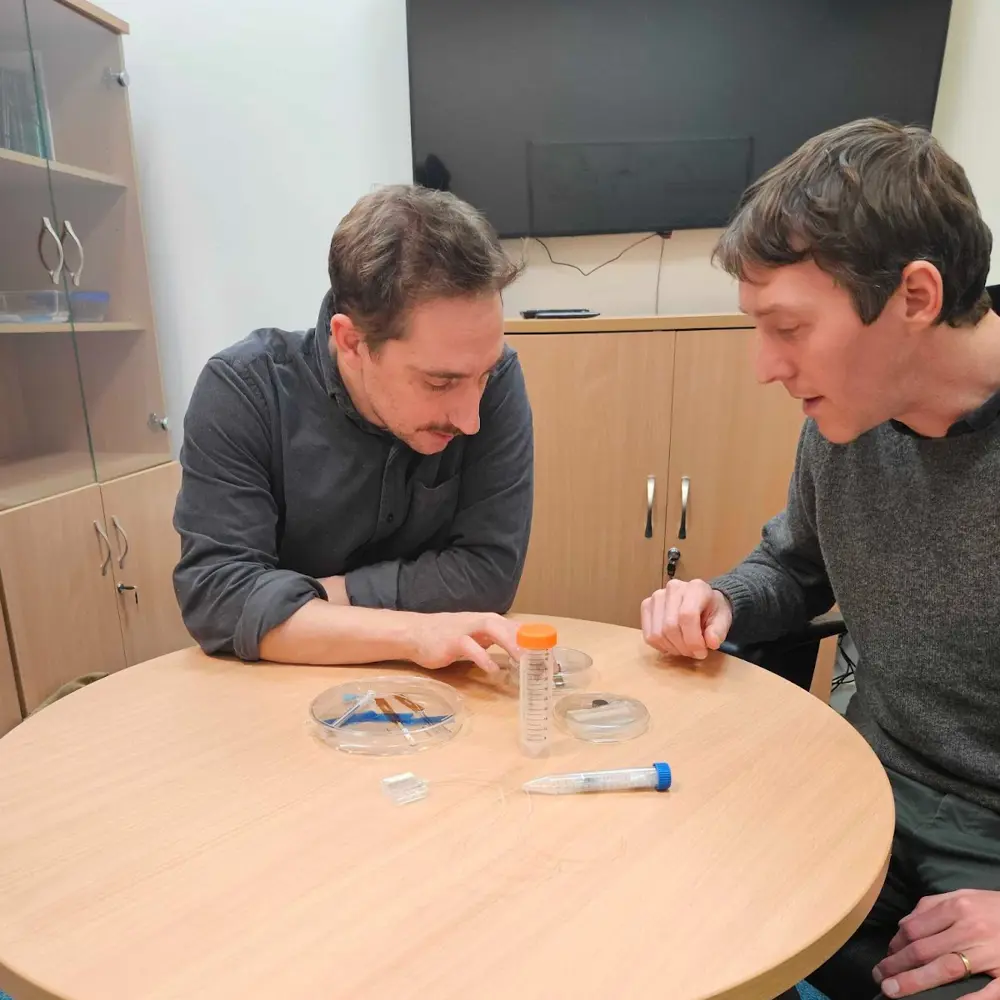 A photo of Jacques and another person looking at items on a table.