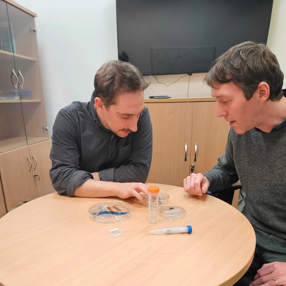 A photo of Jacques and another person looking at items on a table.