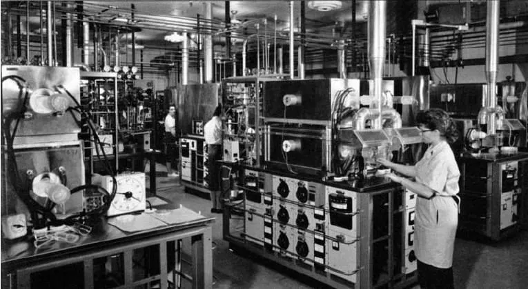 A black and white photo of a woman working in a factory with other people in the background